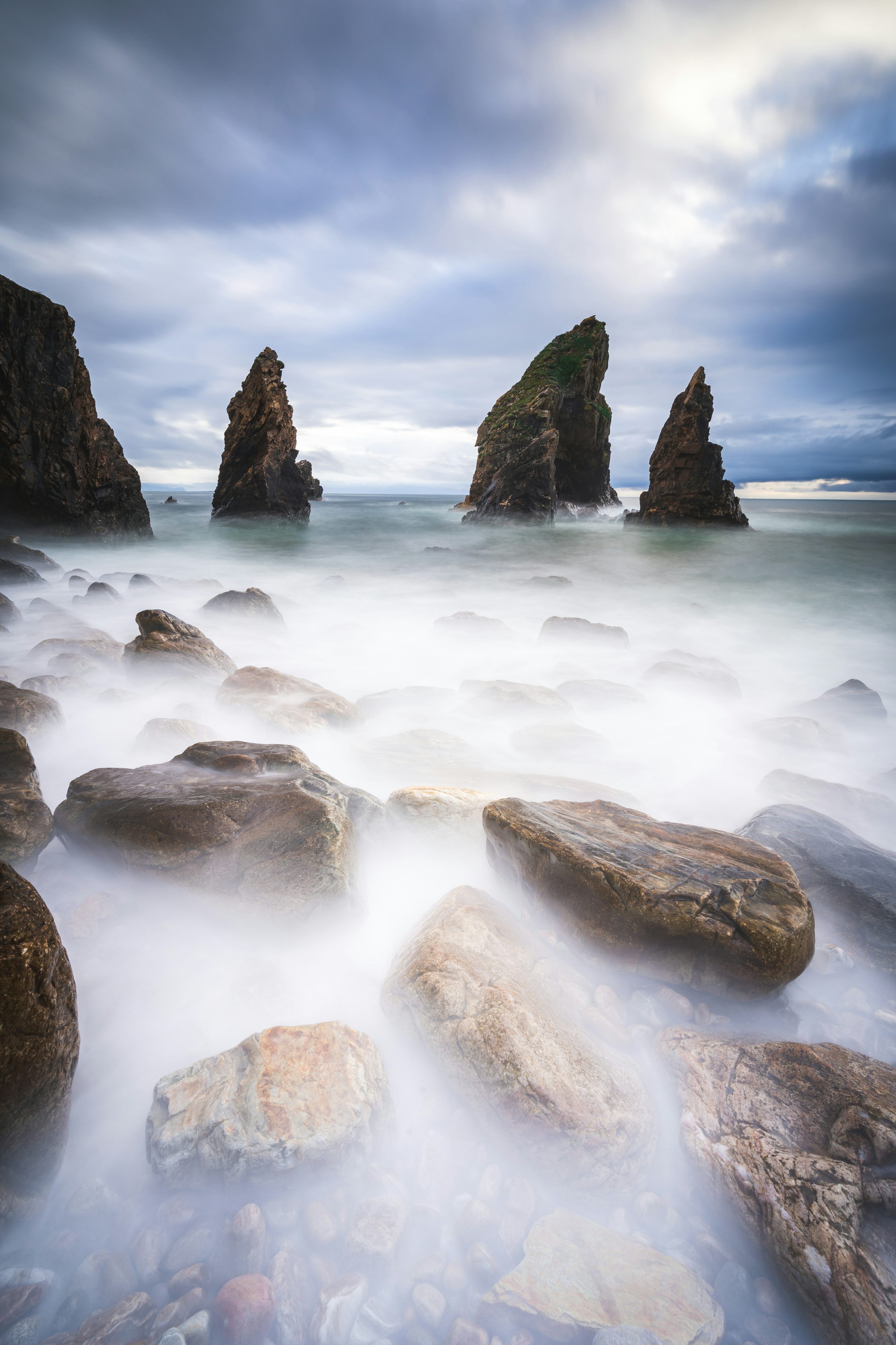 A long exposure photo of rocks in the ocean