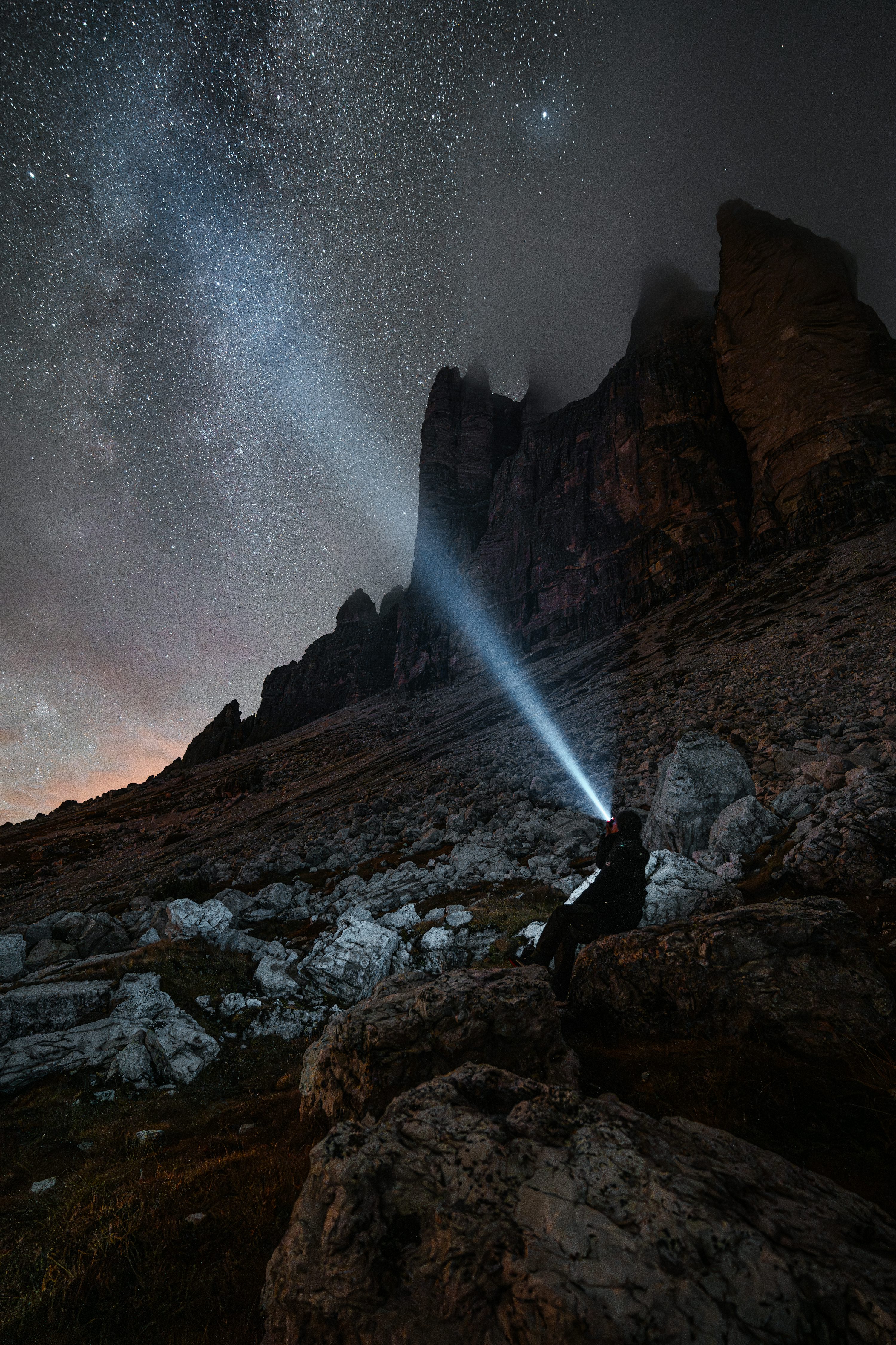 A person standing on top of a mountain under a night sky