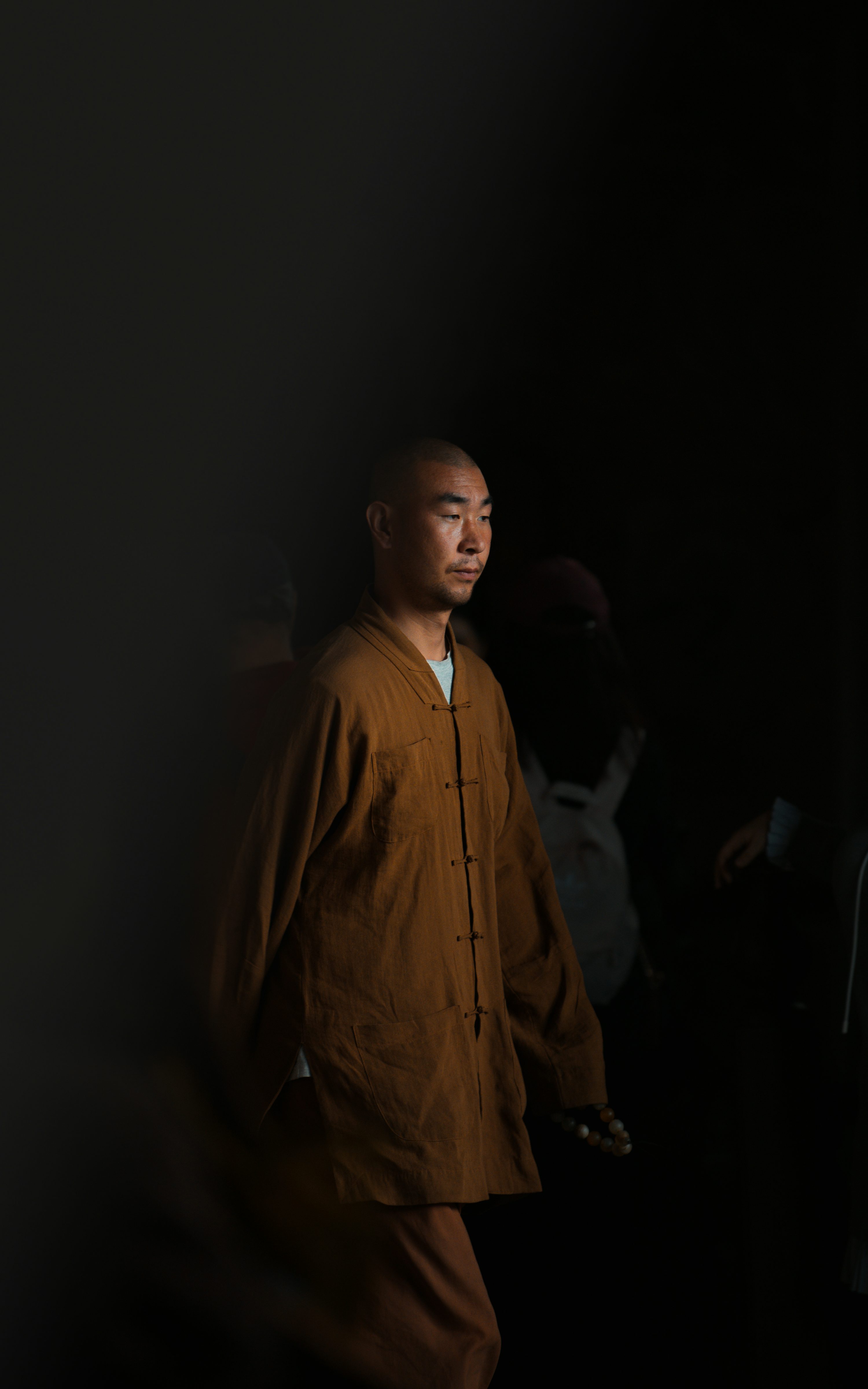 A man standing in a dark room with his hands in his pockets