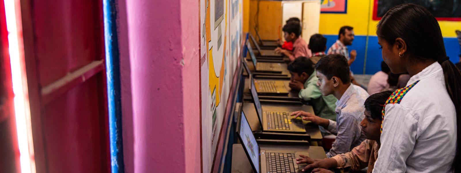 An instructor oversees young people in a computer lab.