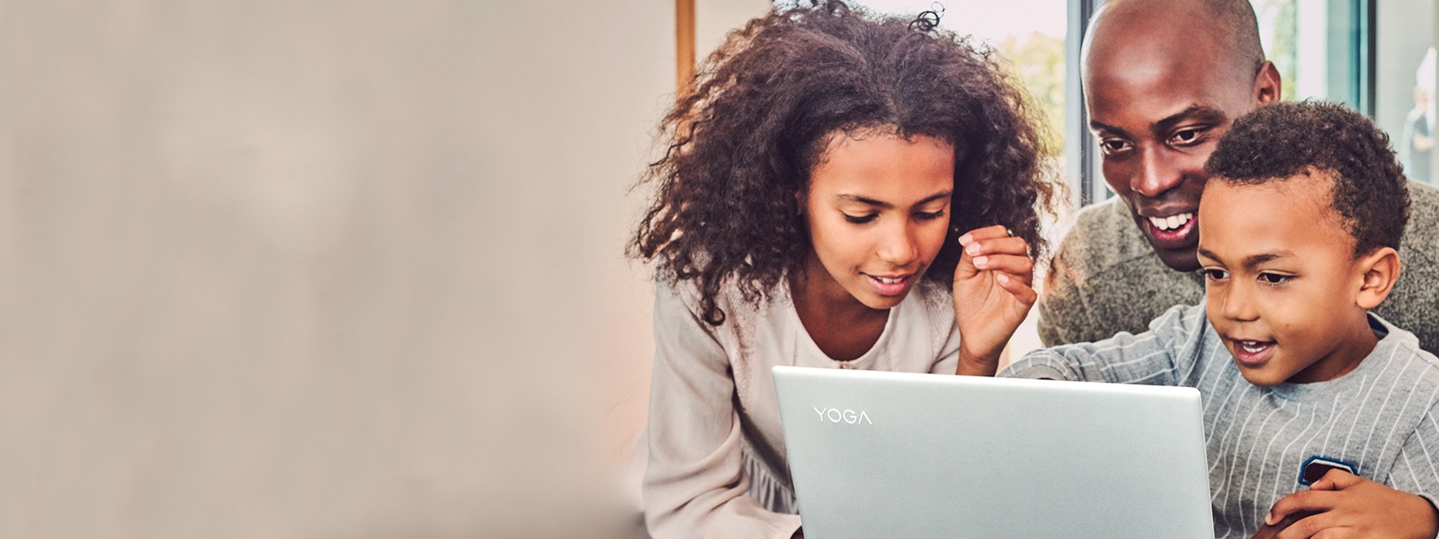 A father and two children look at a laptop together.