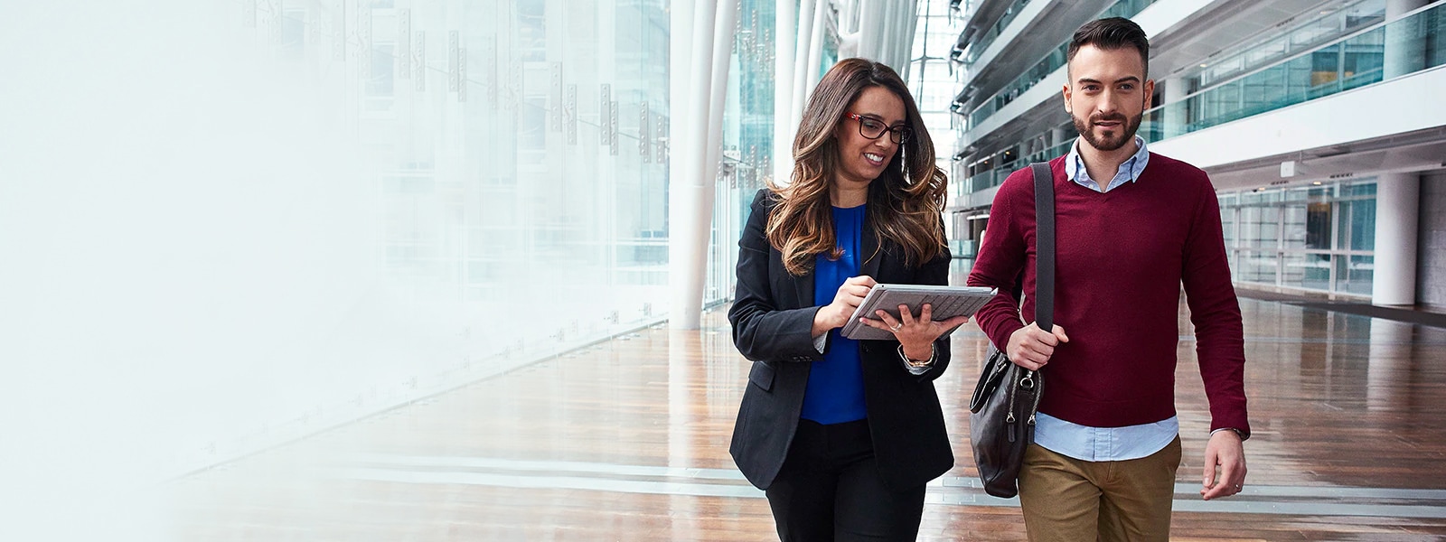 A man and woman walk side by side inside of an office building.