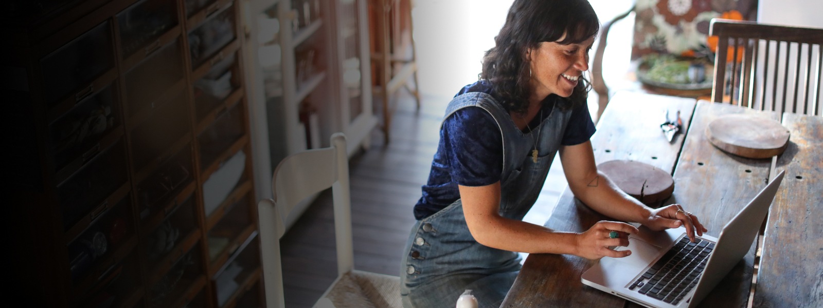 A casually-dressed woman works on a laptop at home.