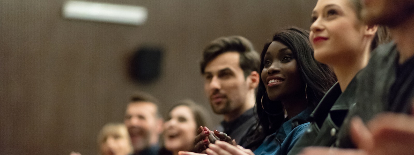 People in an audience applauding in a theater.