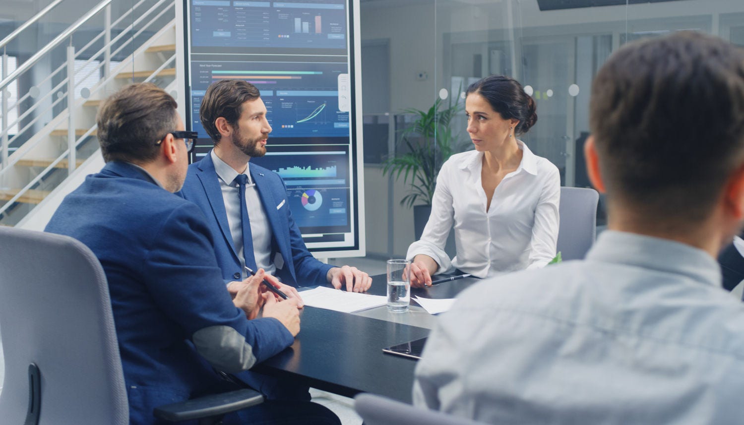 Group of Executives, Lawyers, Businesspeople and Investors Gather at the Table in Corporate Meeting Room to Discuss Business, Finance, Use Tablet Computers, Company Growth and Negotiation Strategy