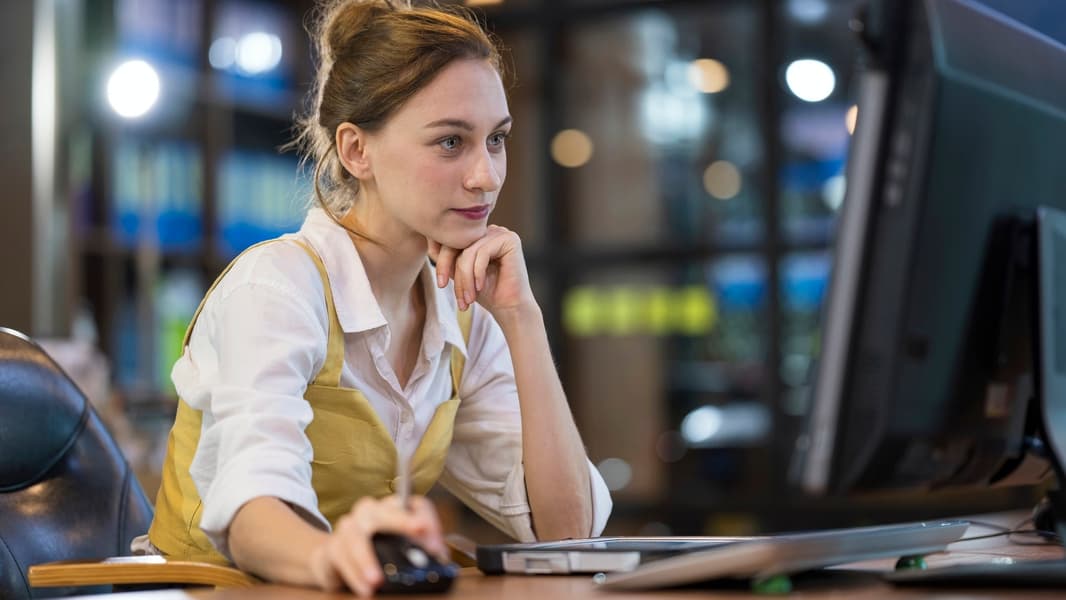 Adult woman working at desk in a business office while reviews or access business strategy and planning.