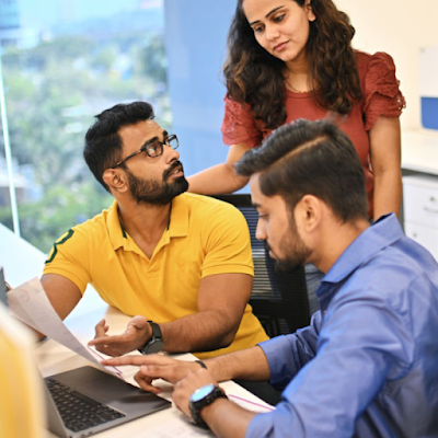 Three co-workers discussing and looking at a laptop