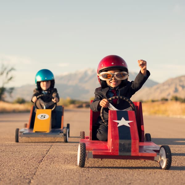 Two young boys dressed in suits racing go karts