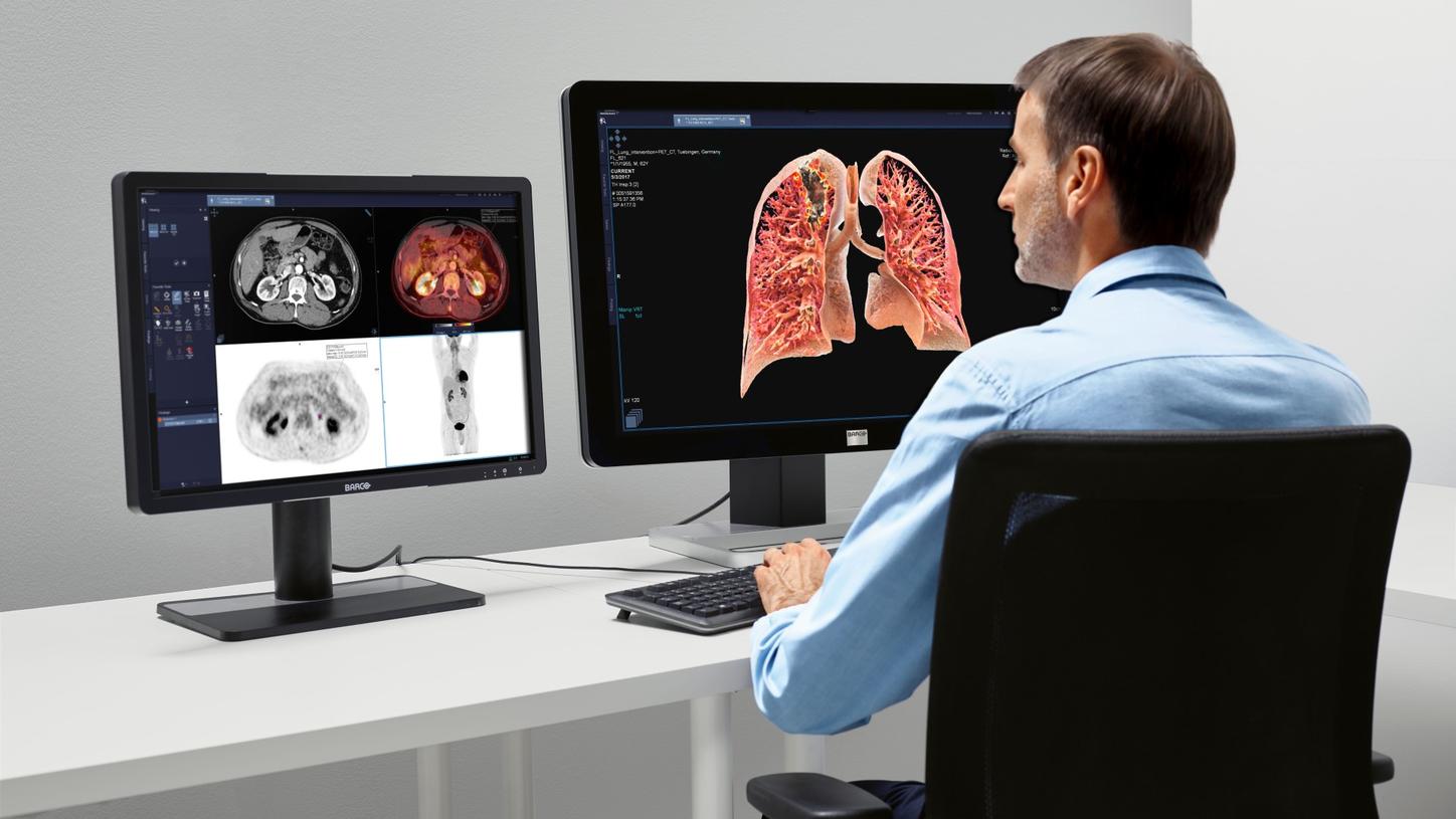 Clinical professional sitting in front of a computer monitor.