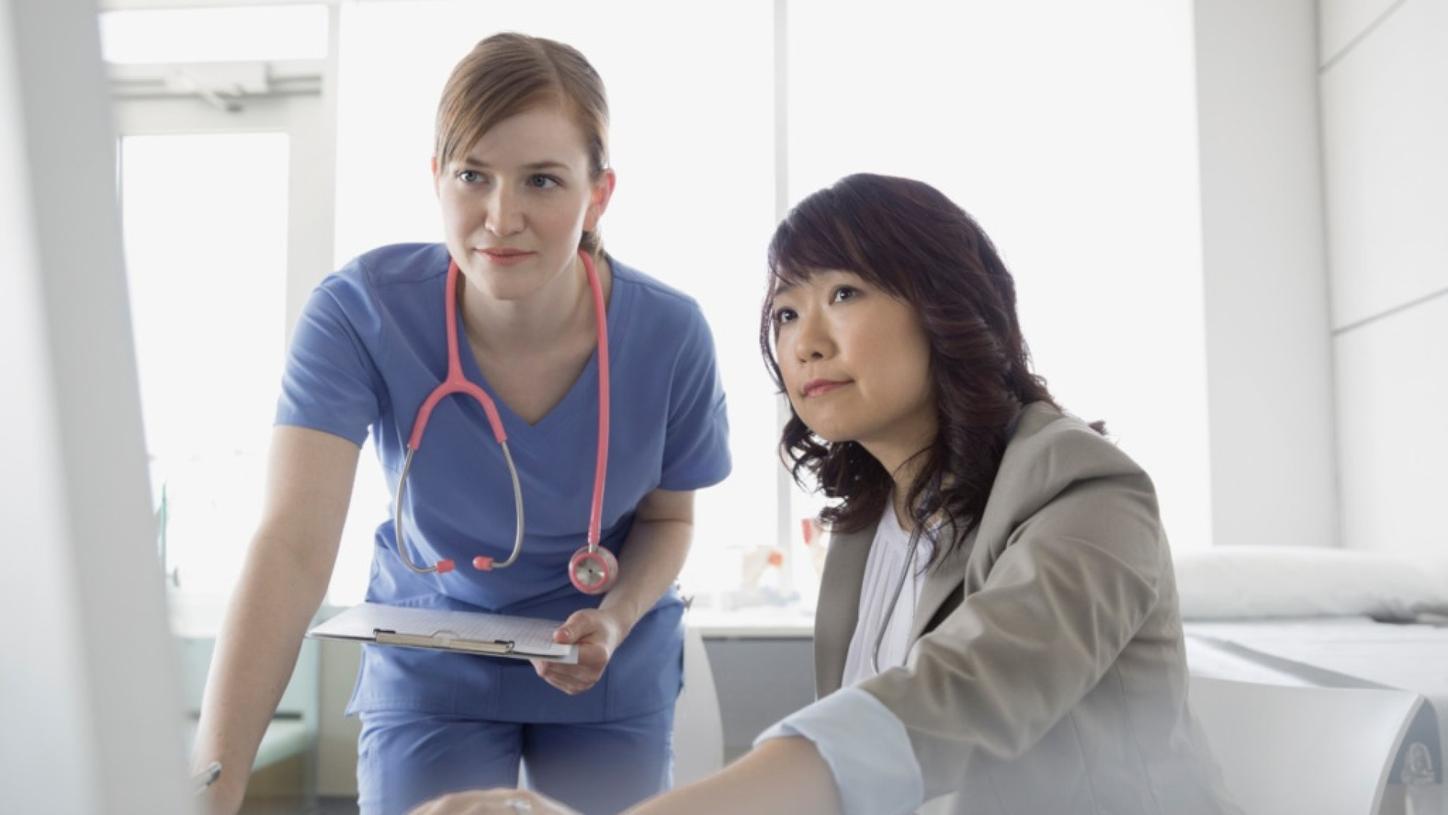 Two medical professionals looking at a computer screen.