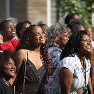 Alumni smiling together watching a performance. 