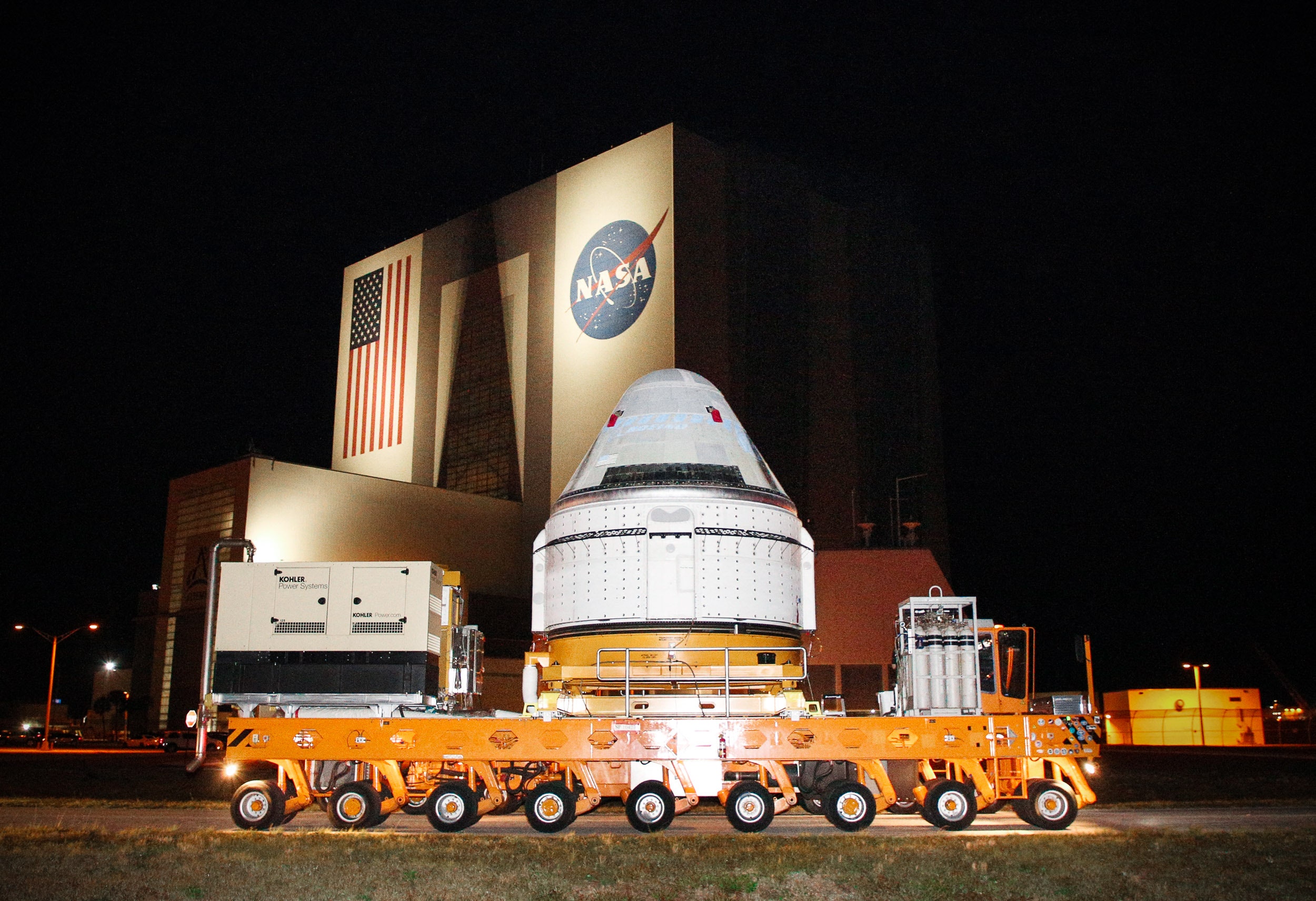 An orange truck carrying a white space capsule