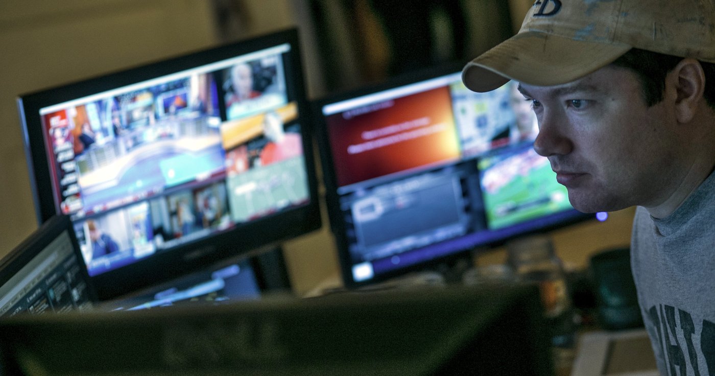 A man is surrounded by computer screens