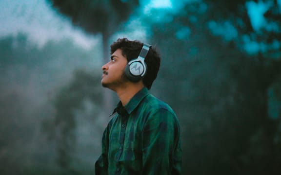 A person looking into the distance wearing over-ear headphones.