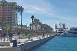 A view of the harbour of Malaga, Spain, lined with palm trees on a sunny day