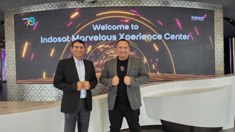 Two men standing in front of a screen stating "Welcome to Indosat Marvelous Xperience Center"