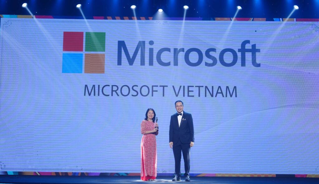 A woman from Microsoft Vietnam receiving trophy from a man on stage of HR Asia Awards 2024