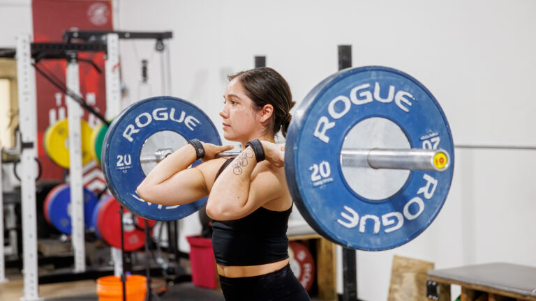 Photo of Jourdan Delacruz lifting a large weight.