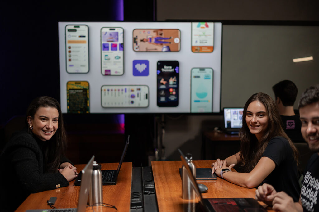 Multiple people sitting at a table with a projector screen in the background