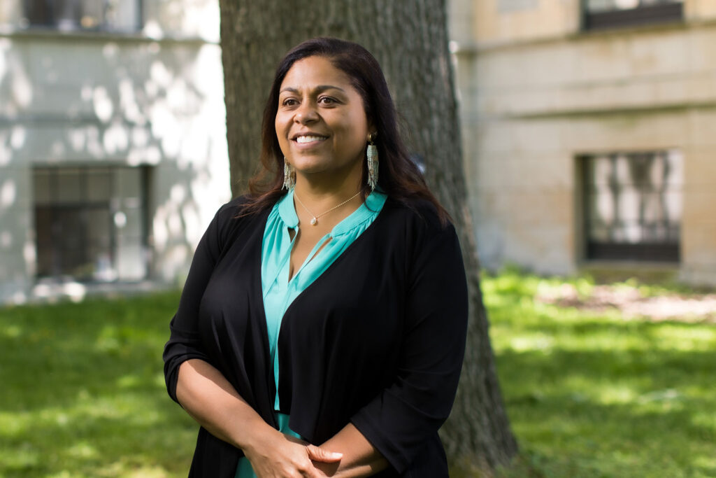 Woman stands in front of tree smiling