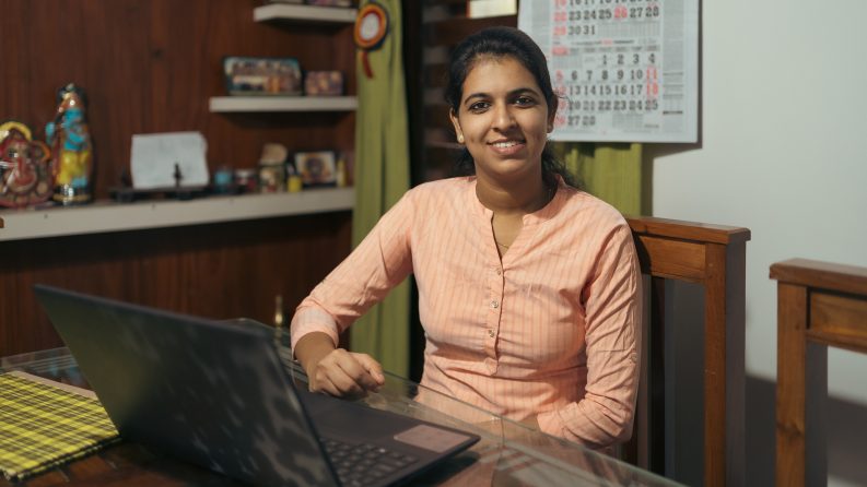 A woman sitting at a dining table working on her laptop