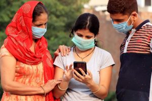 Two woemn and a man look at a smartphone together