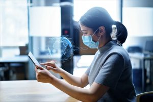 A woman wearing a mask uses her handheld device