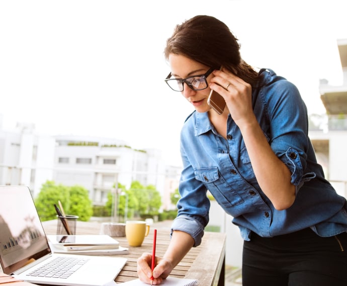 Vrouw met telefoon aan het werk.