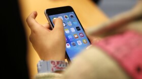 FILE - A child holds an iPhone at an Apple store on Sept. 25, 2015 in Chicago. Parents — and even some teens themselves — are growing increasingly concerned about the effects of social media use on young people. (AP Photo/Kiichiro Sato, File)