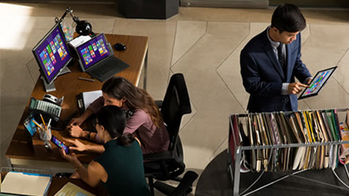 Two women working at desk and man with tablet