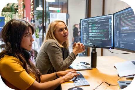 Two people sitting at a desk looking at computer screens