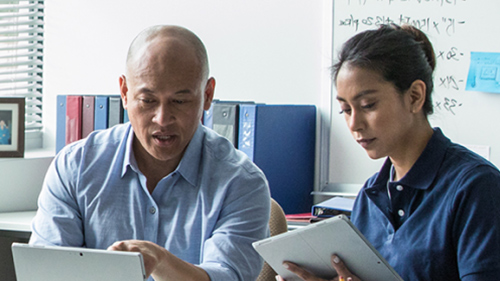 Two coworkers working on tablets