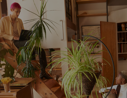 A person sitting on stairs with a laptop talking to another person