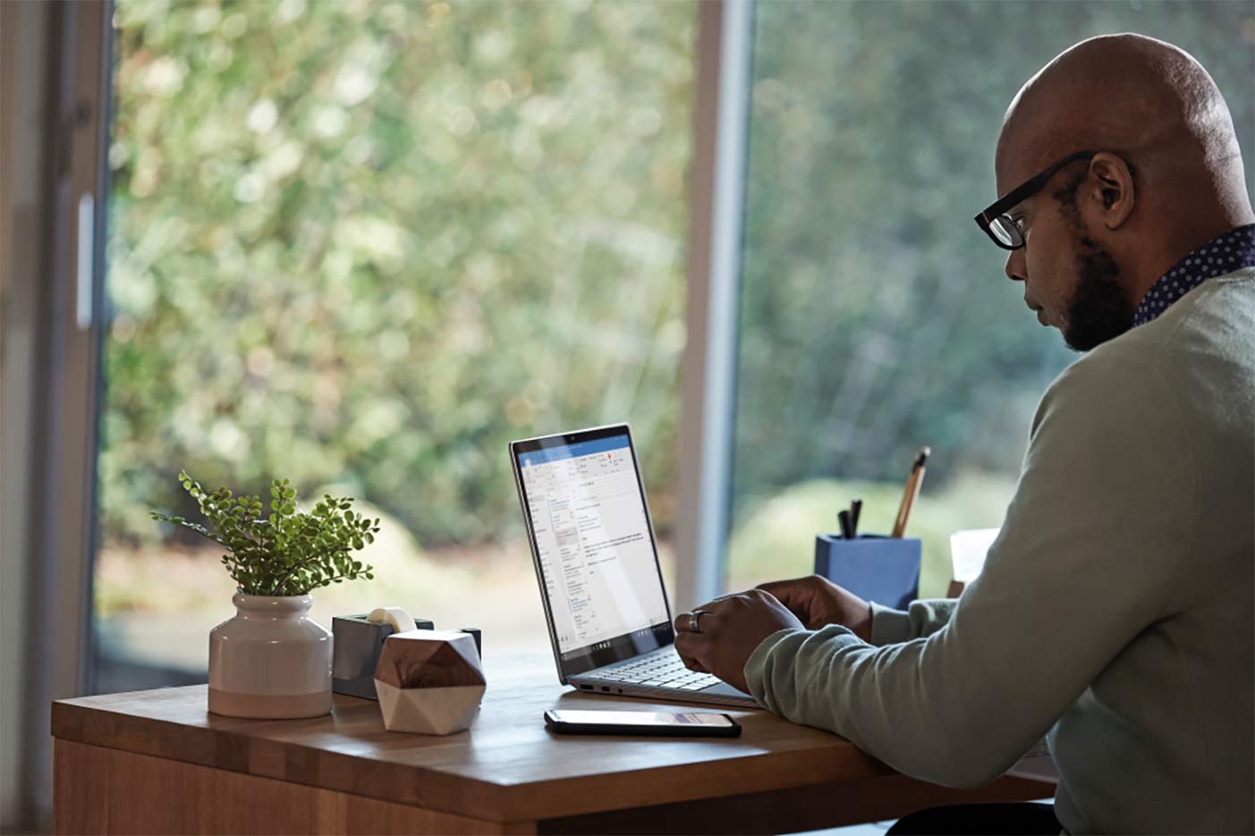 A man works at his laptop in a home office setting