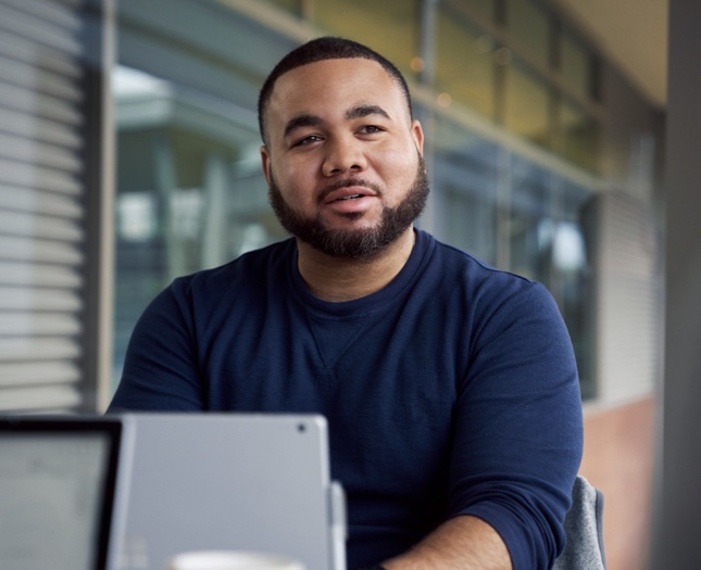 Man sitting outside with a laptop talking