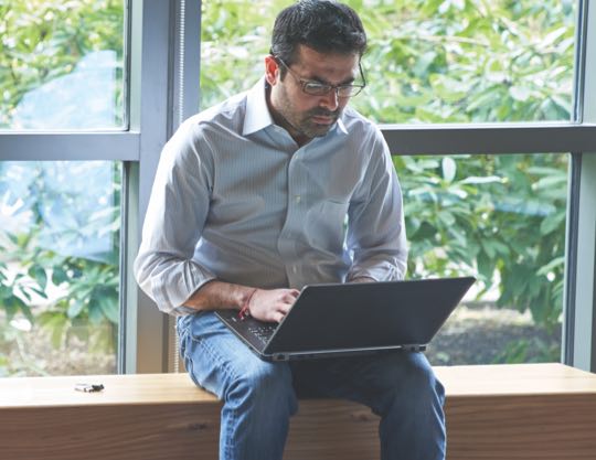 Person on a laptop in front of windows