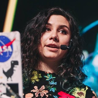 Una presenting from behind her laptop with a headset microphone.