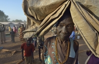 A woman carries her tarp early in the morning in a camp for over 5,000 internally displaced persons in an Episcopal Church compound in Wau, South Sudan. Most of the families here were displaced by violence early in 2017, after a larger number took refuge in other church sites when widespread armed conflict engulfed Wau in June 2016. Most of the people in this camp have no shelter, and use a tarp or mats to lay on the ground at night.