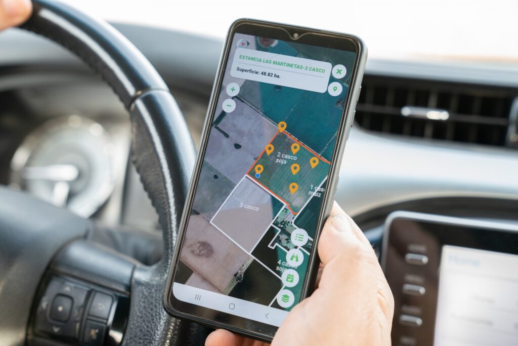 A man’s hand holding a smart phone inside the cab of a truck