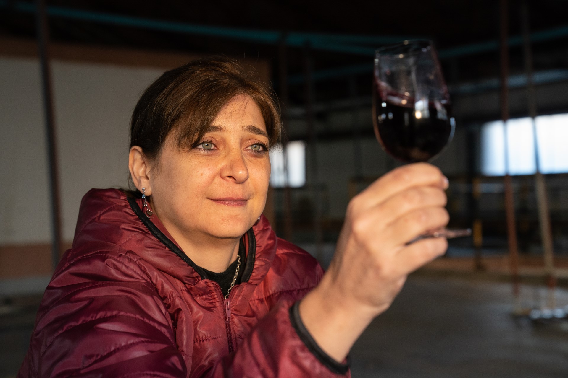 A woman looks at a glass of wine in her hand