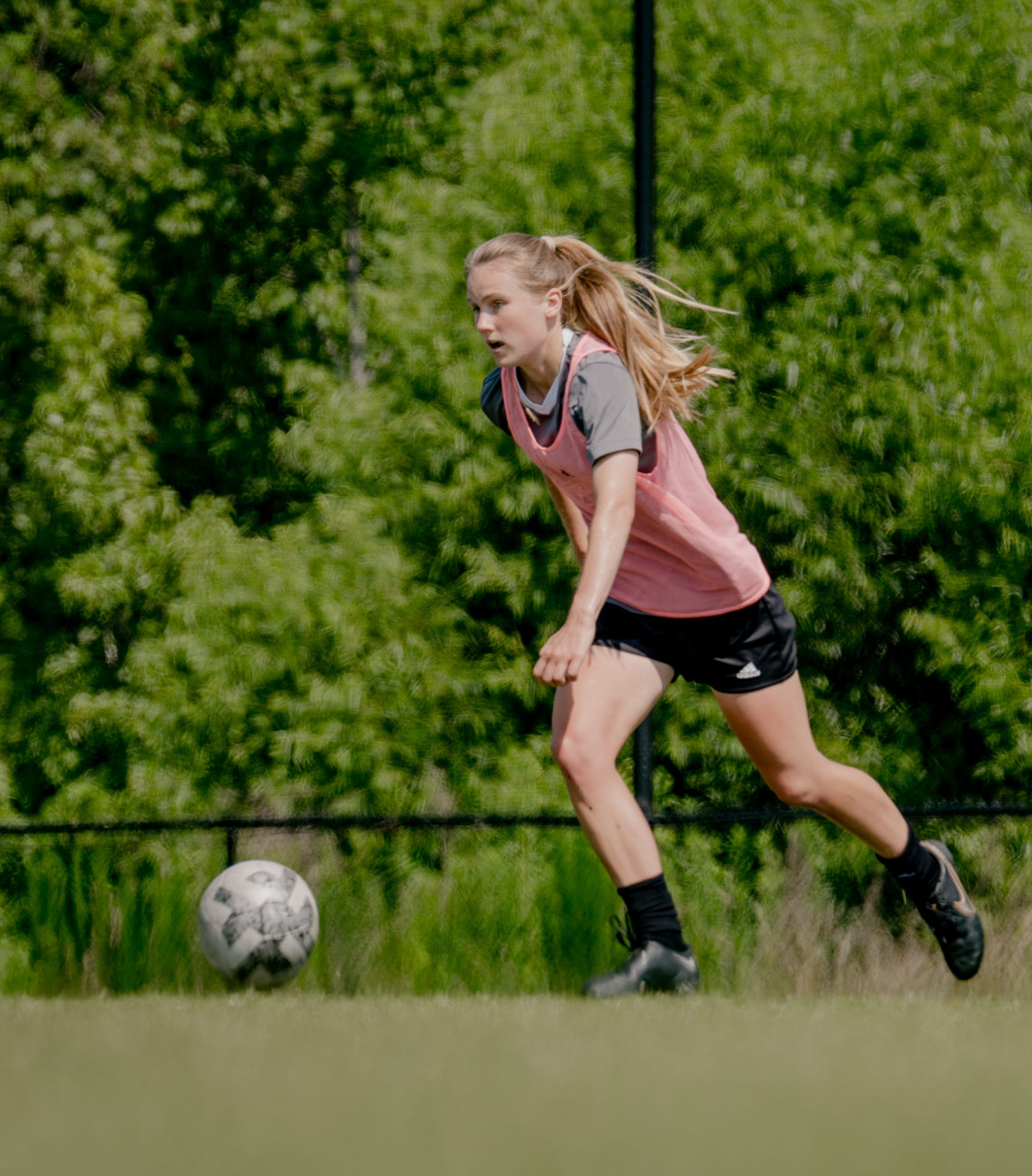 Kate Duffy dribbles a soccer ball on the field with other players behind her.