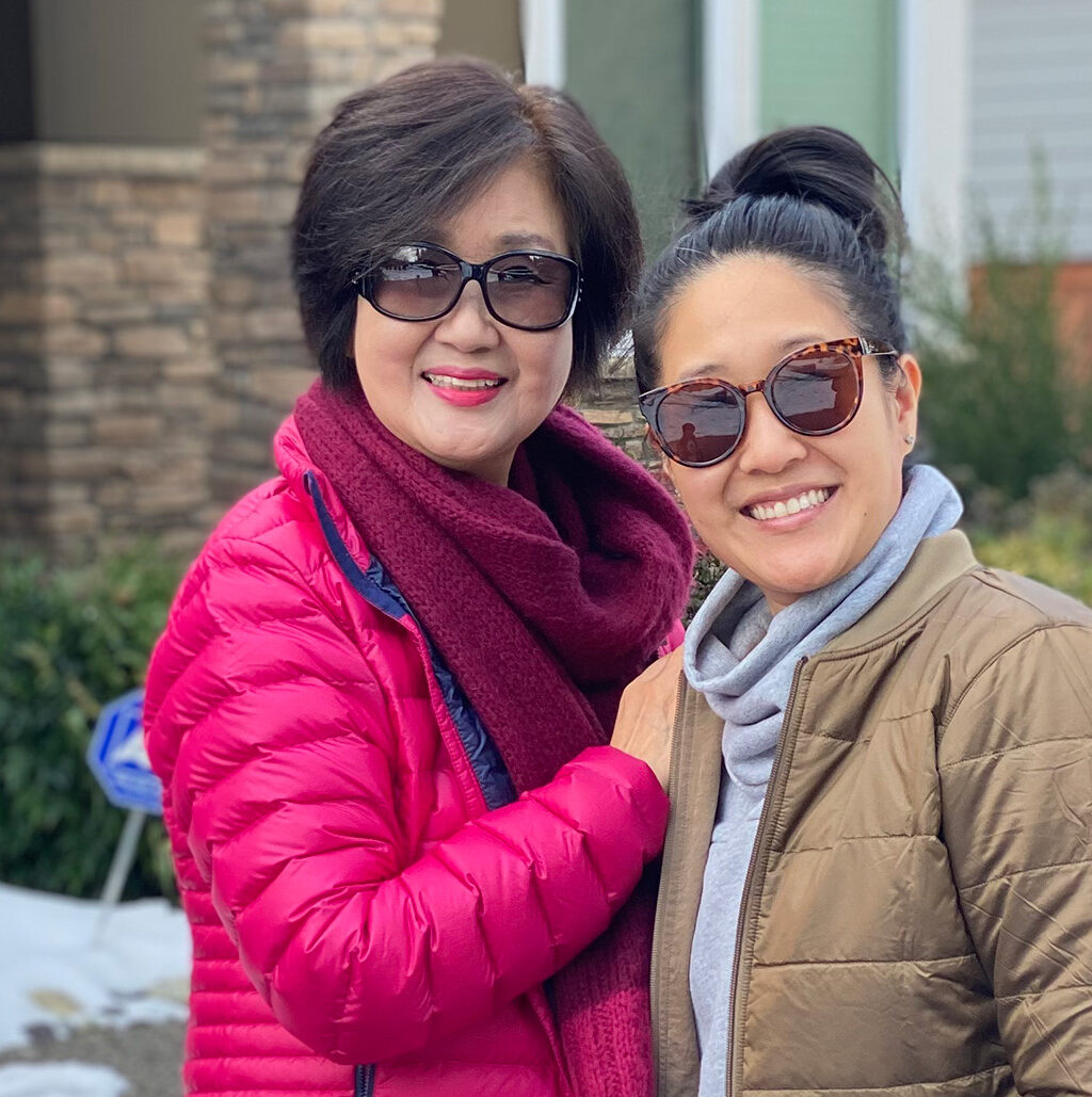 Woman stands smiling next to her mother outside in the snow