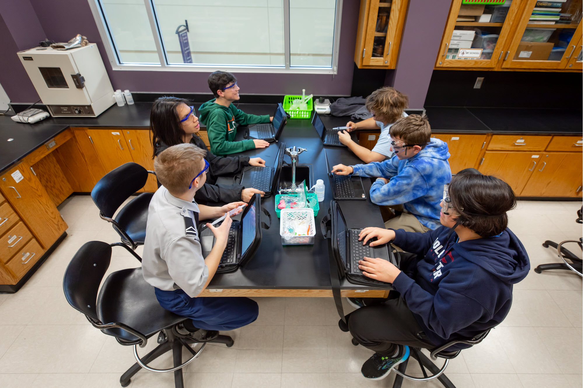 Picture of a group of students sitting around a table in a classroom comparing notes.