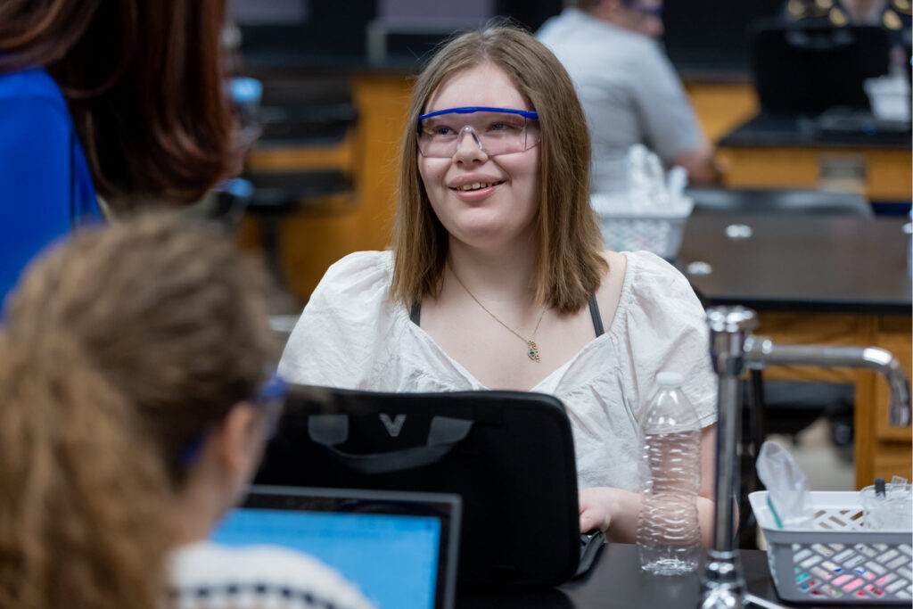 Picture of high school student, Madisyn Sanders sitting behind a laptop in a classroom setting.