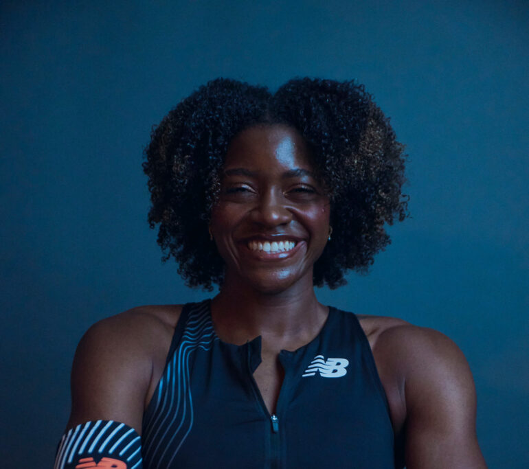 Woman stands smiling with her arms folded