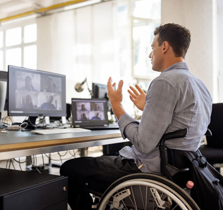 Man in a wheelchair attending a Teams meeting on a laptop computer