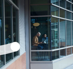 Photo taken from outside a building where two people are talking in an office