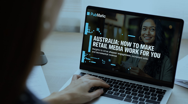 Focused young businesswoman working on her laptop with a report "Australia: How to Make Retail Media Work for You" on the screen