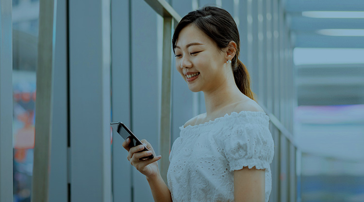 Young asian woman with a paper shopping bag, using smart phone for text messaging or searching for direction