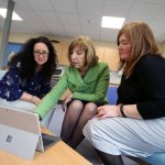 three women gathered around a Microsoft Surface